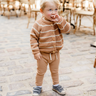 Picture shows little boy standing wearing organic cotton knit cardigan with acorn and cream stripes with Magnetic Buttons.