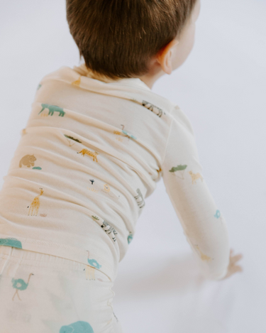 Image shows toddler boy wearing modal pajama set in zoo print.