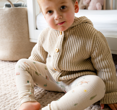 Image shows baby boy wearing organic cotton waffle leggings in camping print.