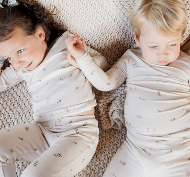 photo shows two toddlers resting on couch and little boy is wearing Paris print pajama set in modal fabric