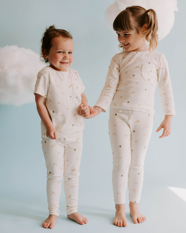 Image of two little girls holding hands while one is wearing organic cotton soft long sleeve tee in playground print with an adorable pocket. 