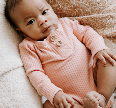 Baby girl wearing organic cotton rib bodysuit with Magnetic Buttons for easy changing in strawberries and cream color. Bodysuit opens with Magnetic Buttons at the neck as well as crotch.