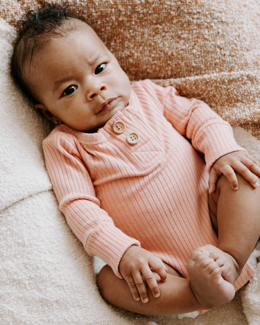 Baby girl wearing organic cotton rib bodysuit with Magnetic Buttons for easy changing in strawberries and cream color. Bodysuit opens with Magnetic Buttons at the neck as well as crotch.